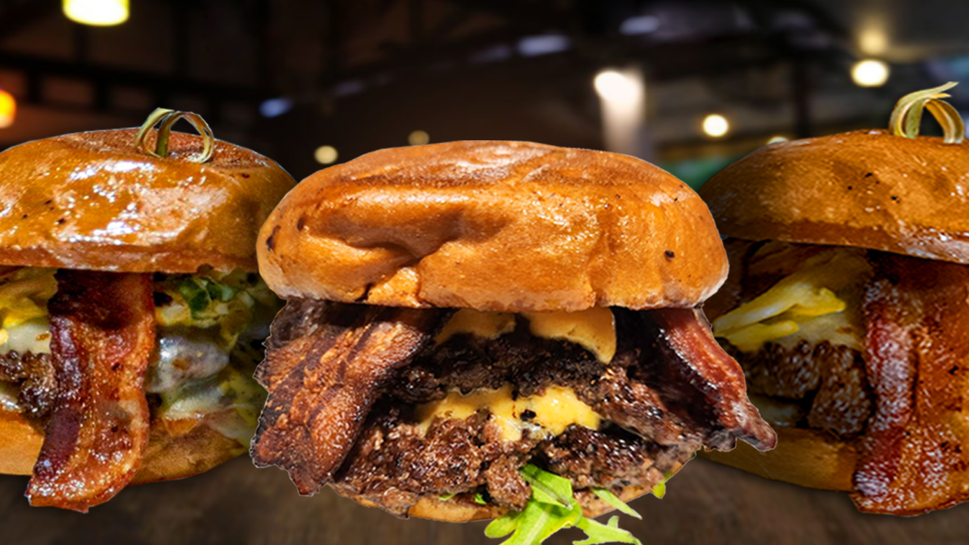 Smash burgers assembled with multiple beef patties, bacon, lettuce, and cheese on a bun.