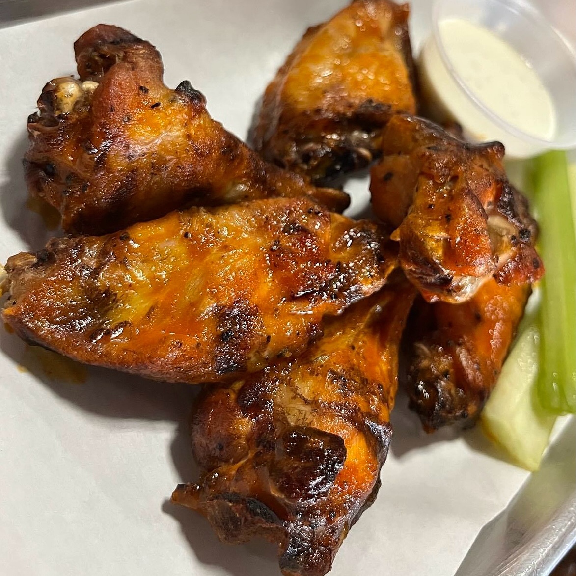 A serving of six smoked chicken wings with a side of celery and ranch.
